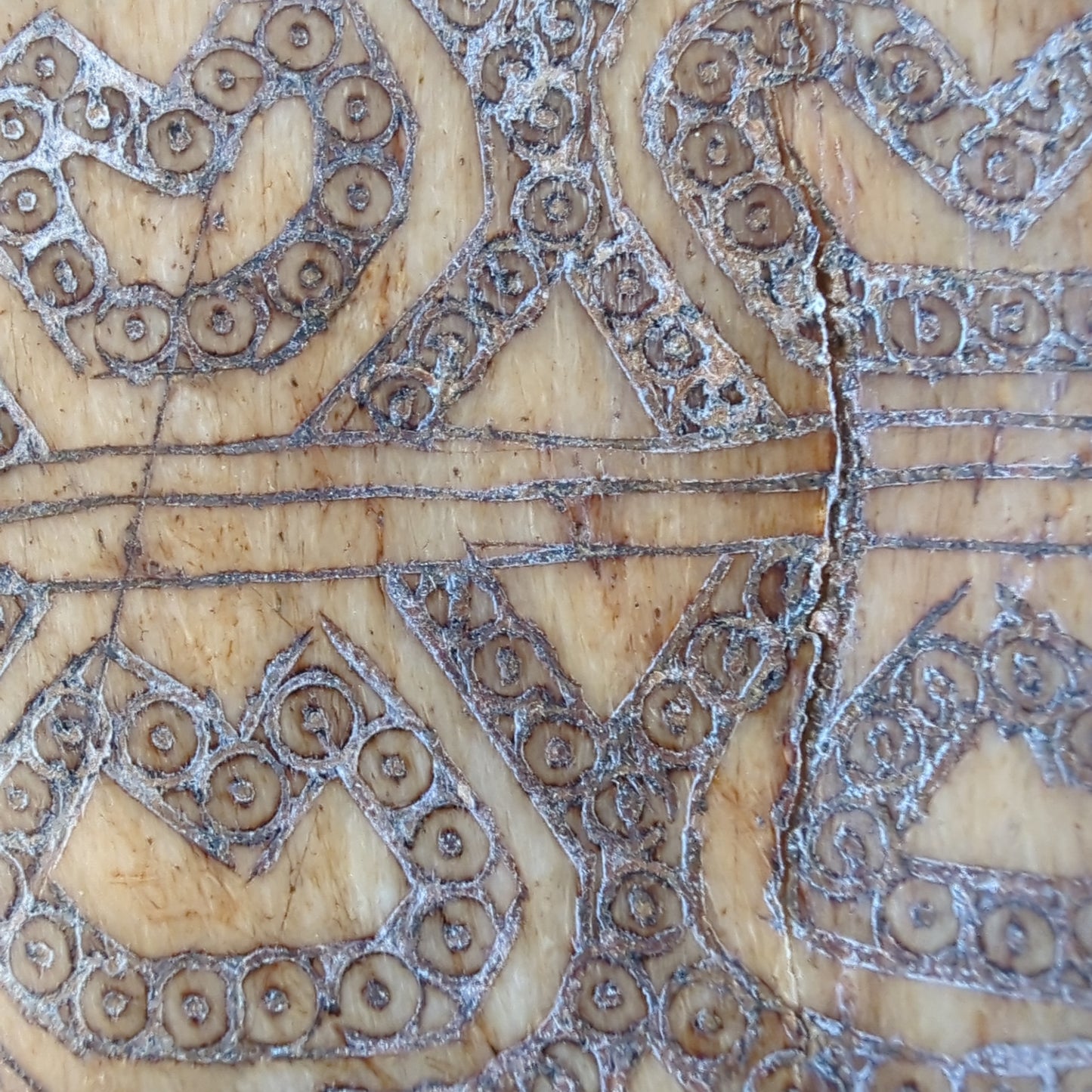 Pattern Detail: A close-up of the intricate spiral and geometric patterns carved into the body of the amulet.