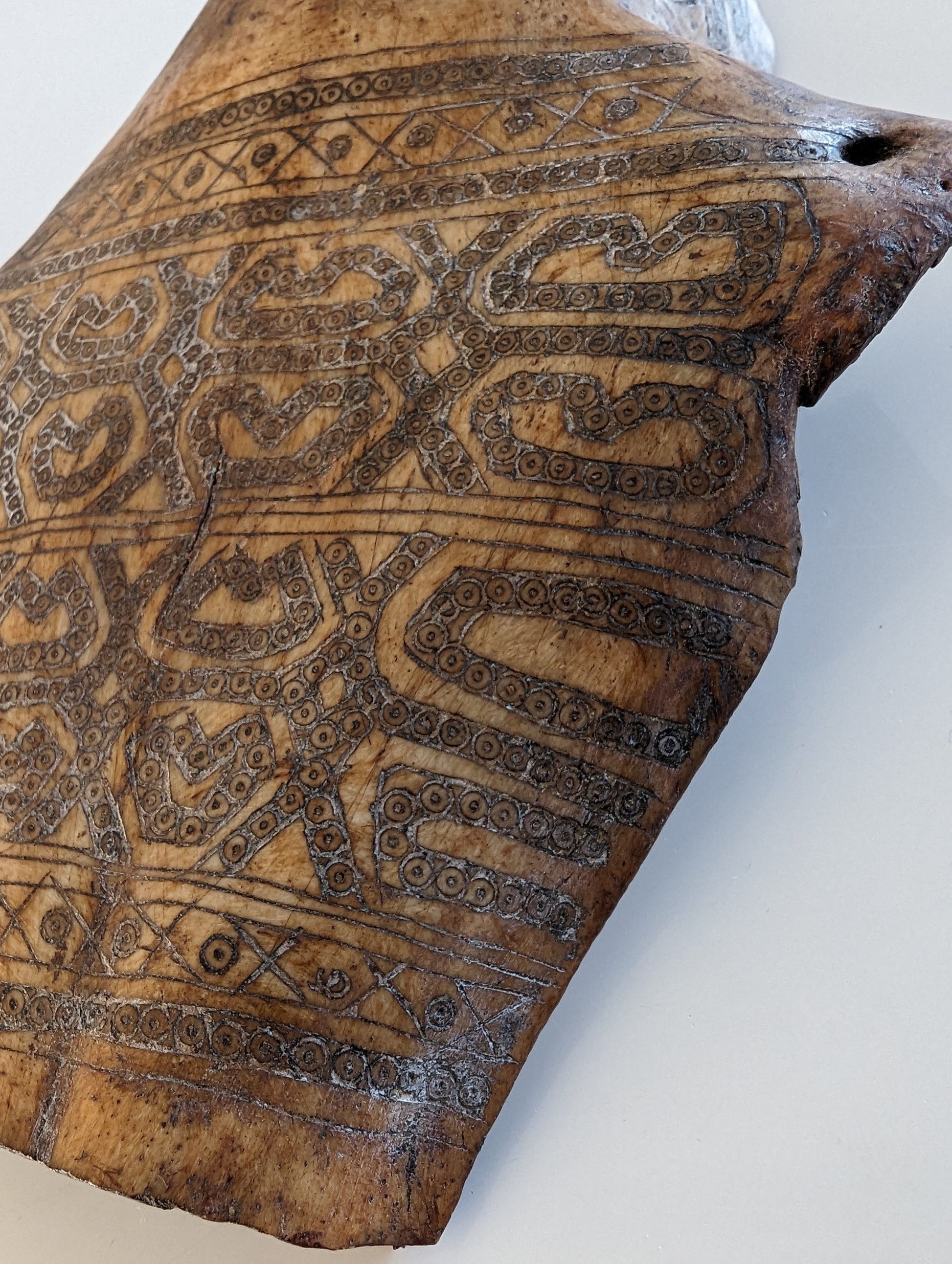 Top-Down Detail: A close-up, top-down view of the amulet's face and the patterns carved into the wood below the chin.
