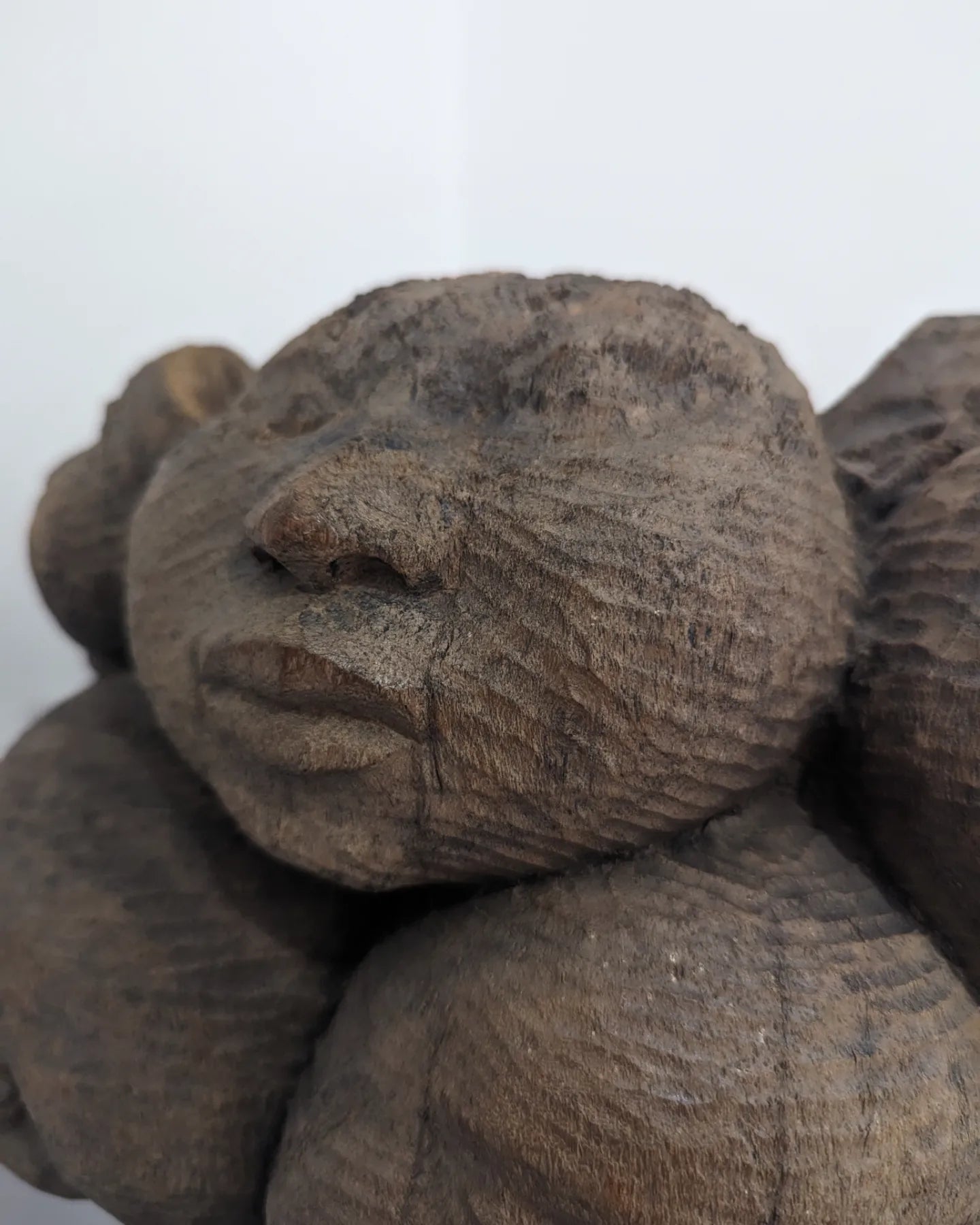 A very tight close-up of a single carved face on the sculpture, emphasizing the intricate details of the eyes, nose, and mouth.