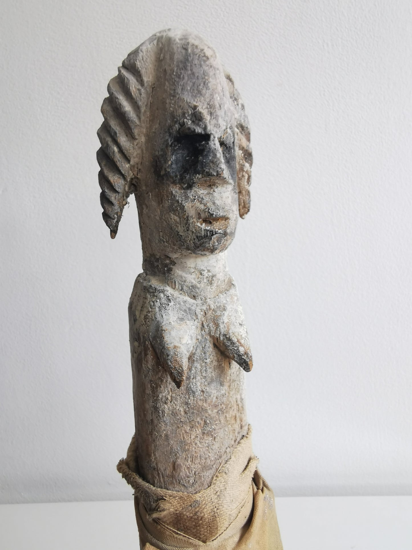 An angled, close-up view of the Ibibio female statuette, showing the details of its carved wooden face, including the eyes, nose, and mouth.