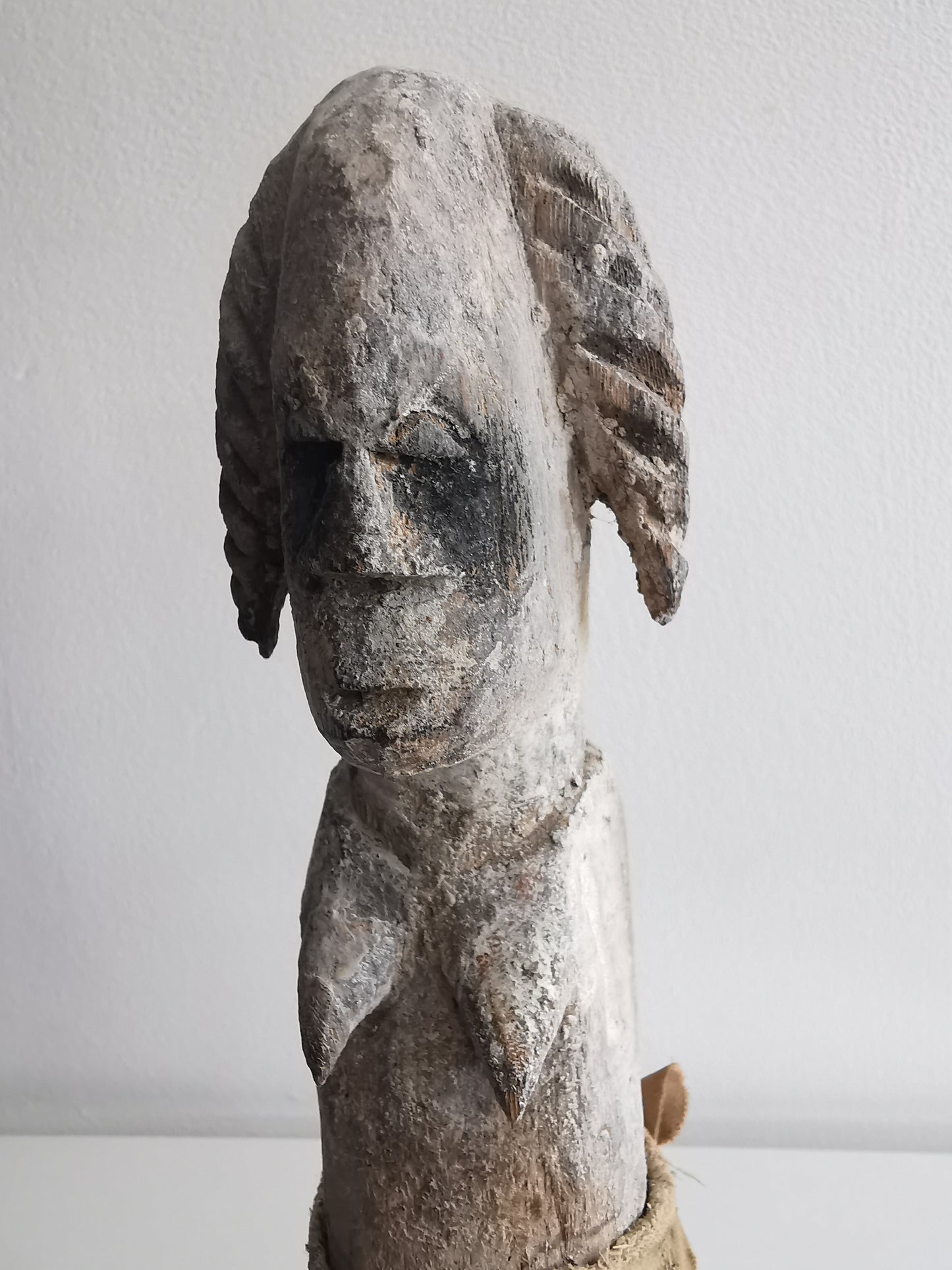 A close-up front shot of the Ibibio female statuette's face and shoulders, highlighting the textured surface of the aged wood and the details of the carved features.