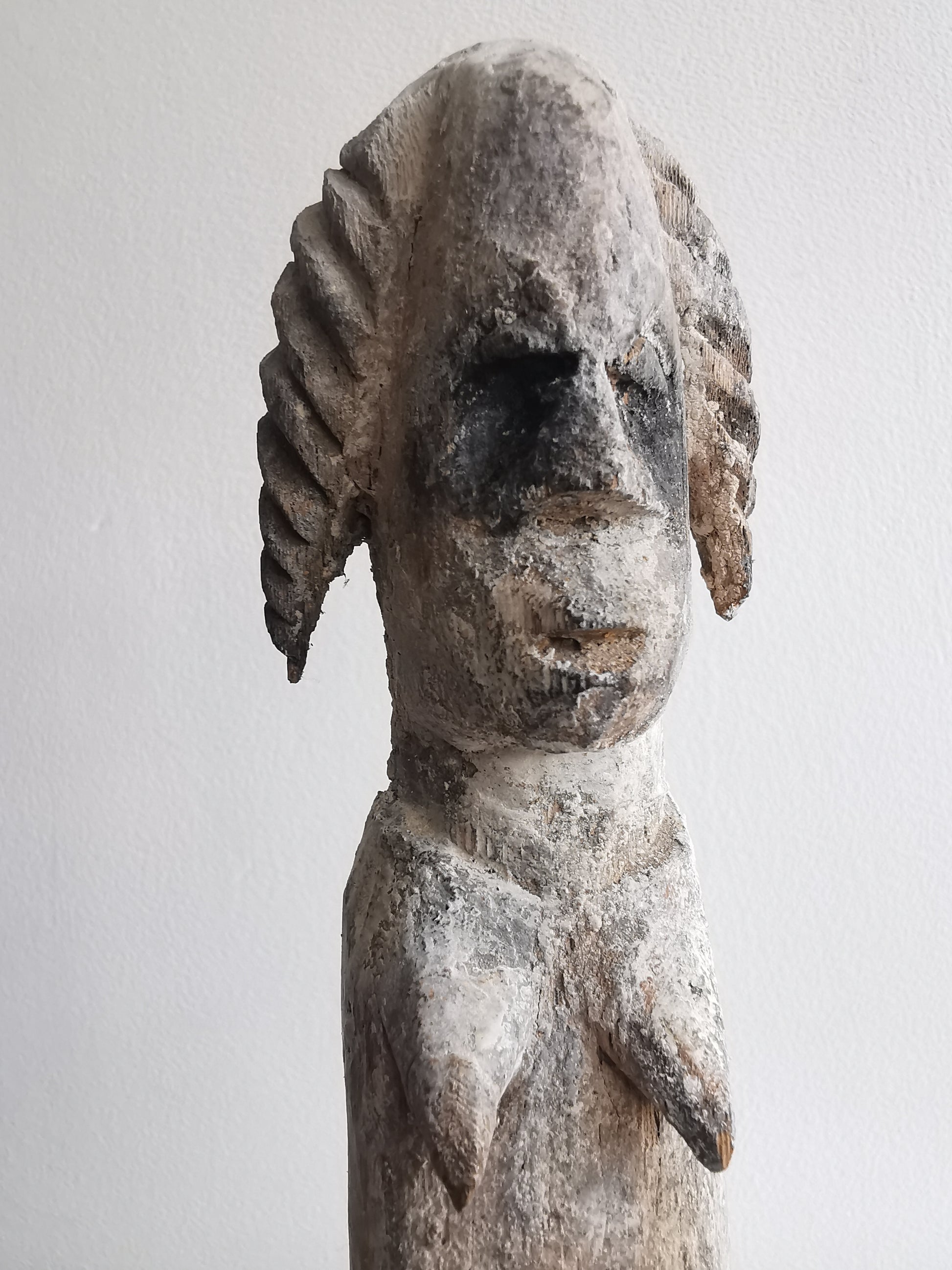 A distant front view of the Ibibio statuette, showing the full piece on the stand from a slightly elevated angle.