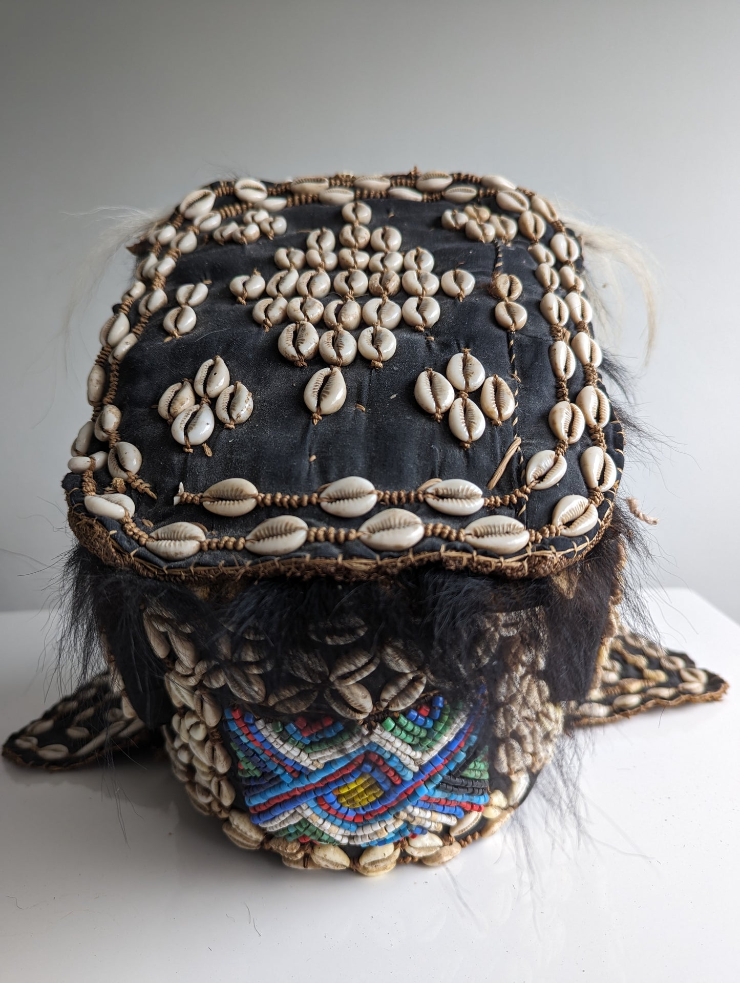 A top-down view of the Kuba helmet mask, showing the elaborate shell-covered headpiece from above and the large, open mouth