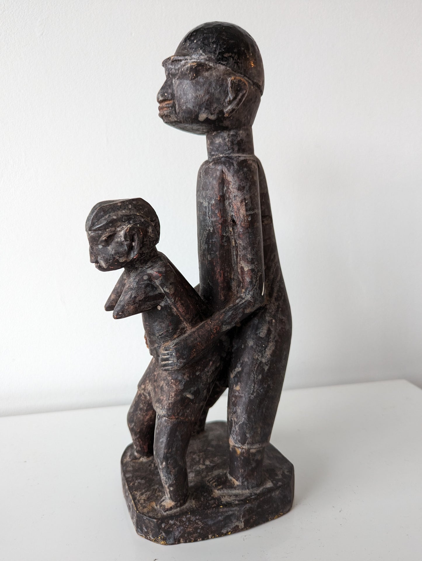 A rear view of a wooden Lobi sculpture of two figures, one standing behind the other in a copulating stance.