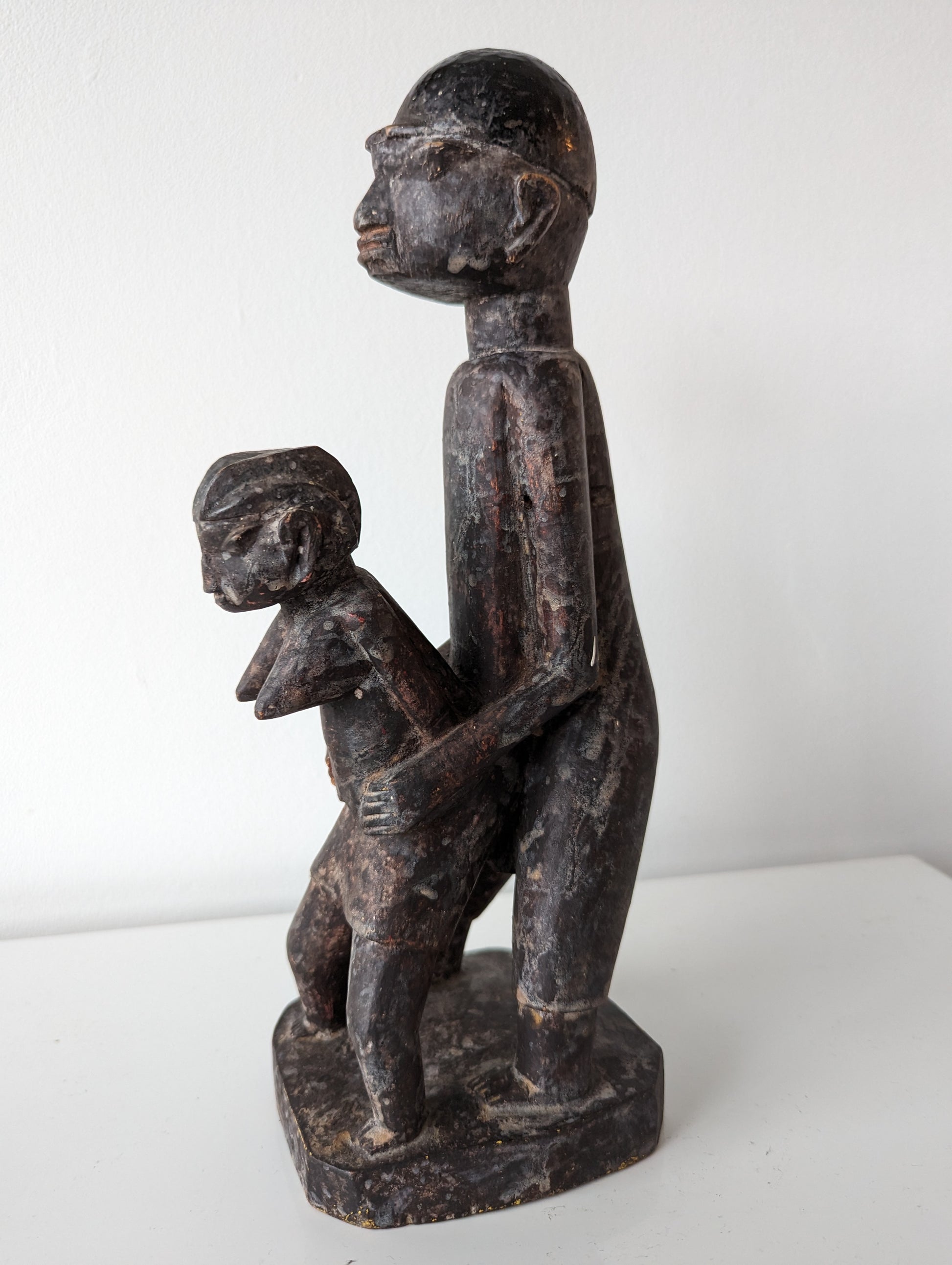 A rear view of a wooden Lobi sculpture of two figures, one standing behind the other in a copulating stance.