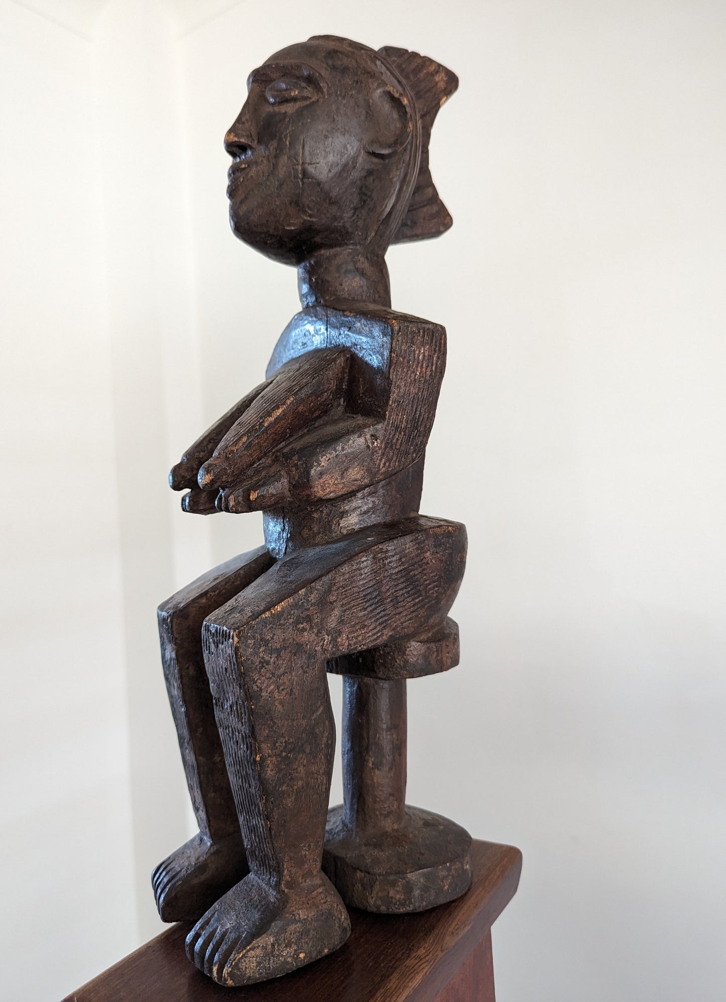 A side profile of the Yoruba statue, showing the full seated figure and its posture.