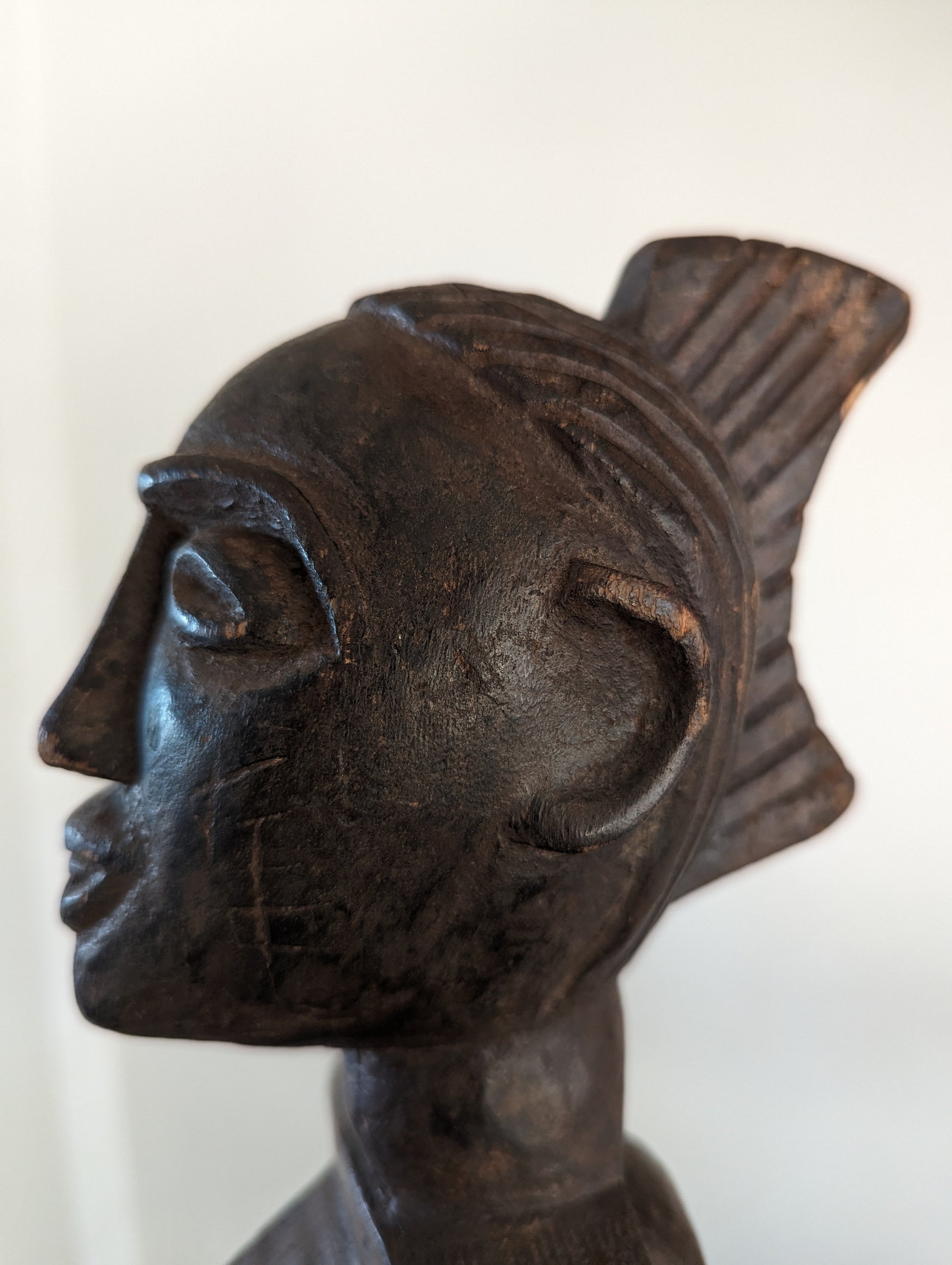 A tight close-up of the statue's face, emphasizing the detailed carving of the eyes, nose, and lips, and the incised patterns on the forehead and headdress.