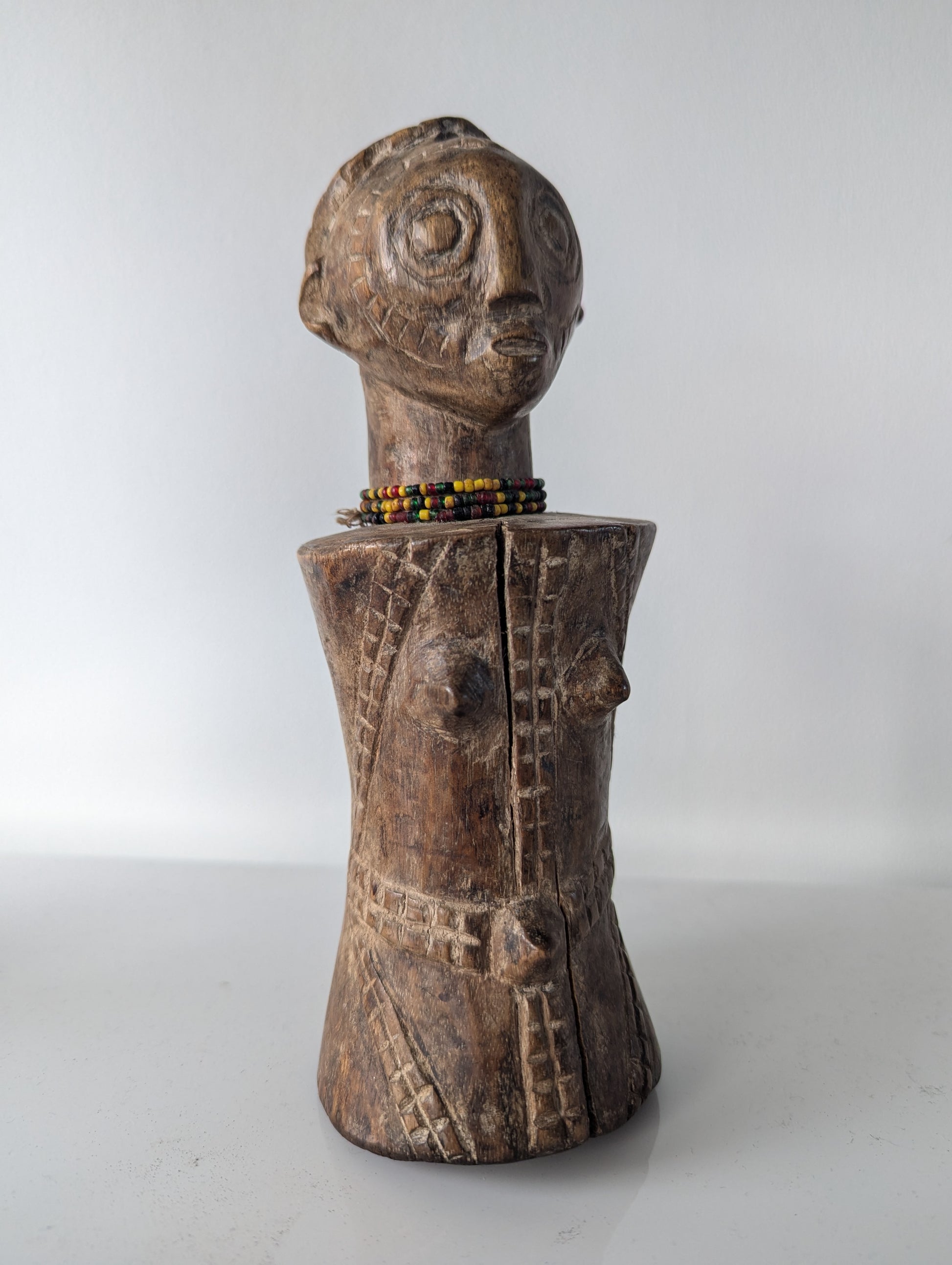 A full-body profile of the tabwa doll. This view reveals the depth of the carving on the torso and the overall shape of the figure.