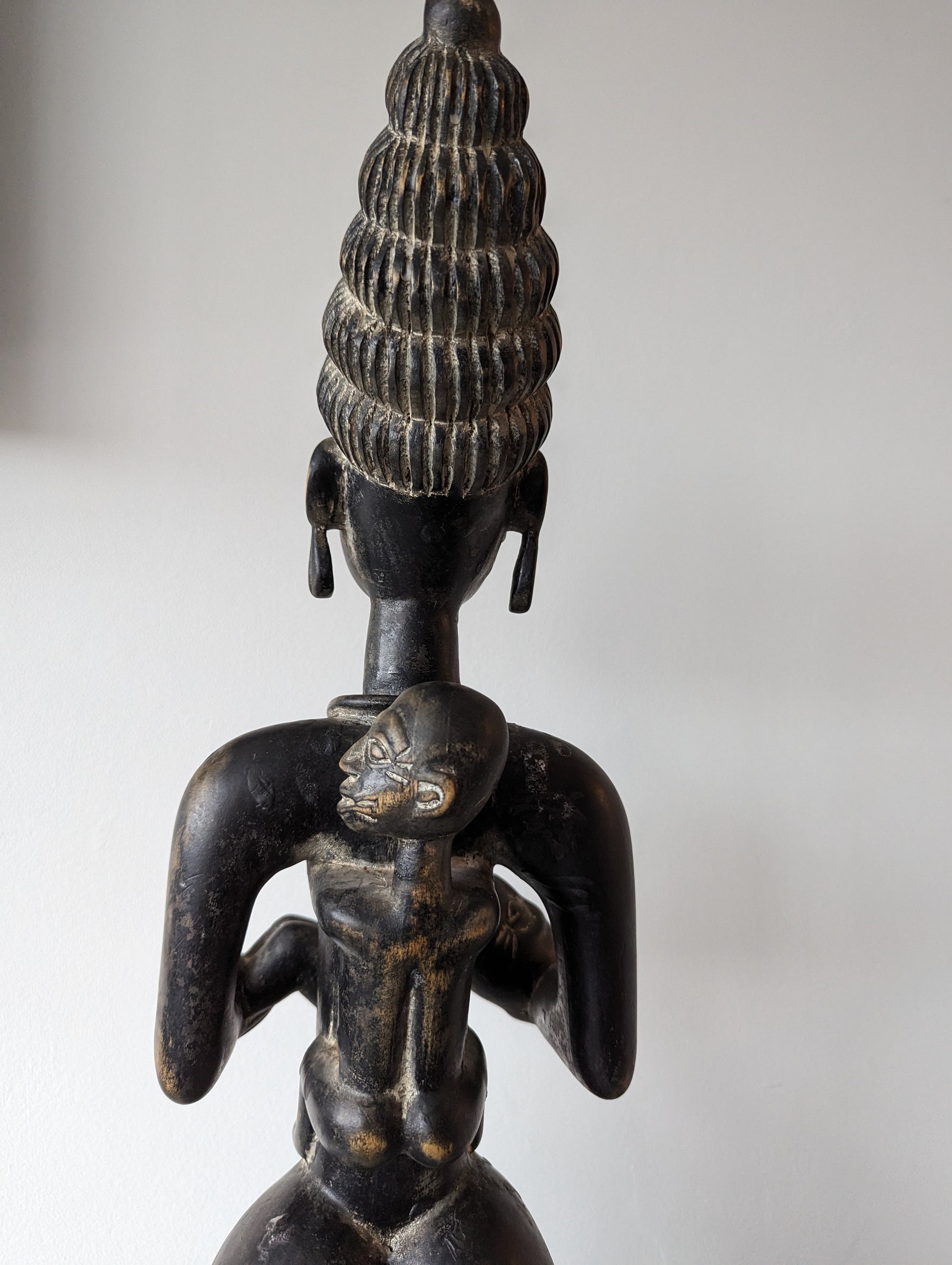 A view of the back of the Yoruba statue, showing the details of the woman's carved headdress and back.