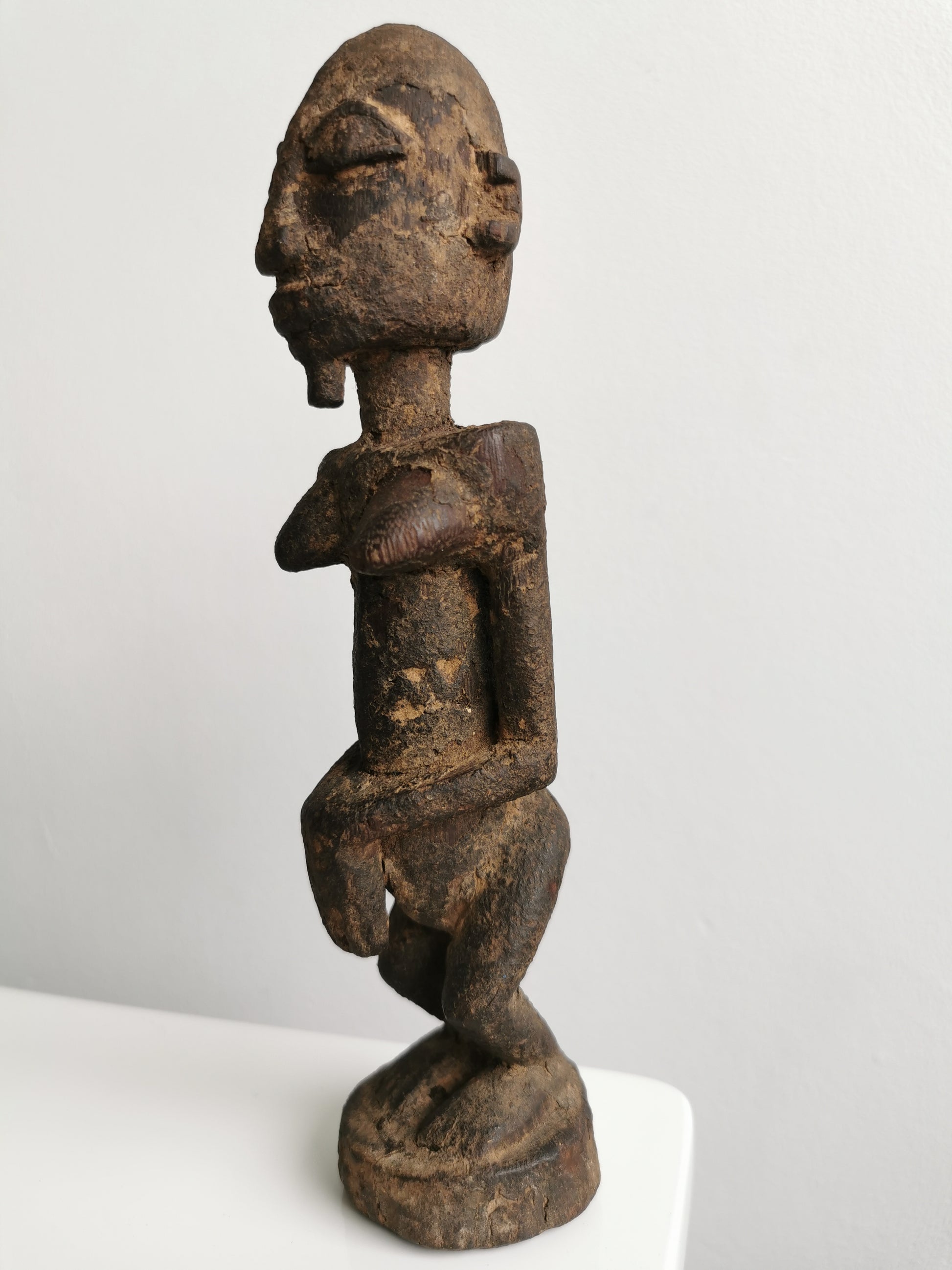 Profile view of the Lobi figure, showing the texture of the wood and the distinct shape of its legs and base.