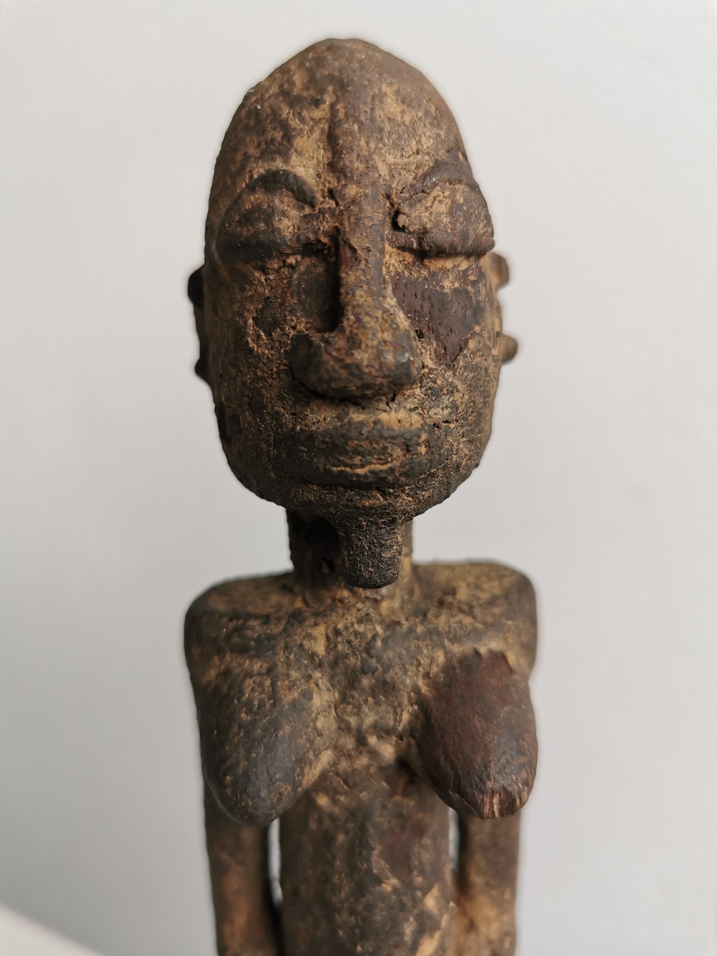 Close-up frontal view of the Lobi figure's face, emphasizing the detailed carvings of its eyes, nose, and mouth, as well as the aged quality of the wood.