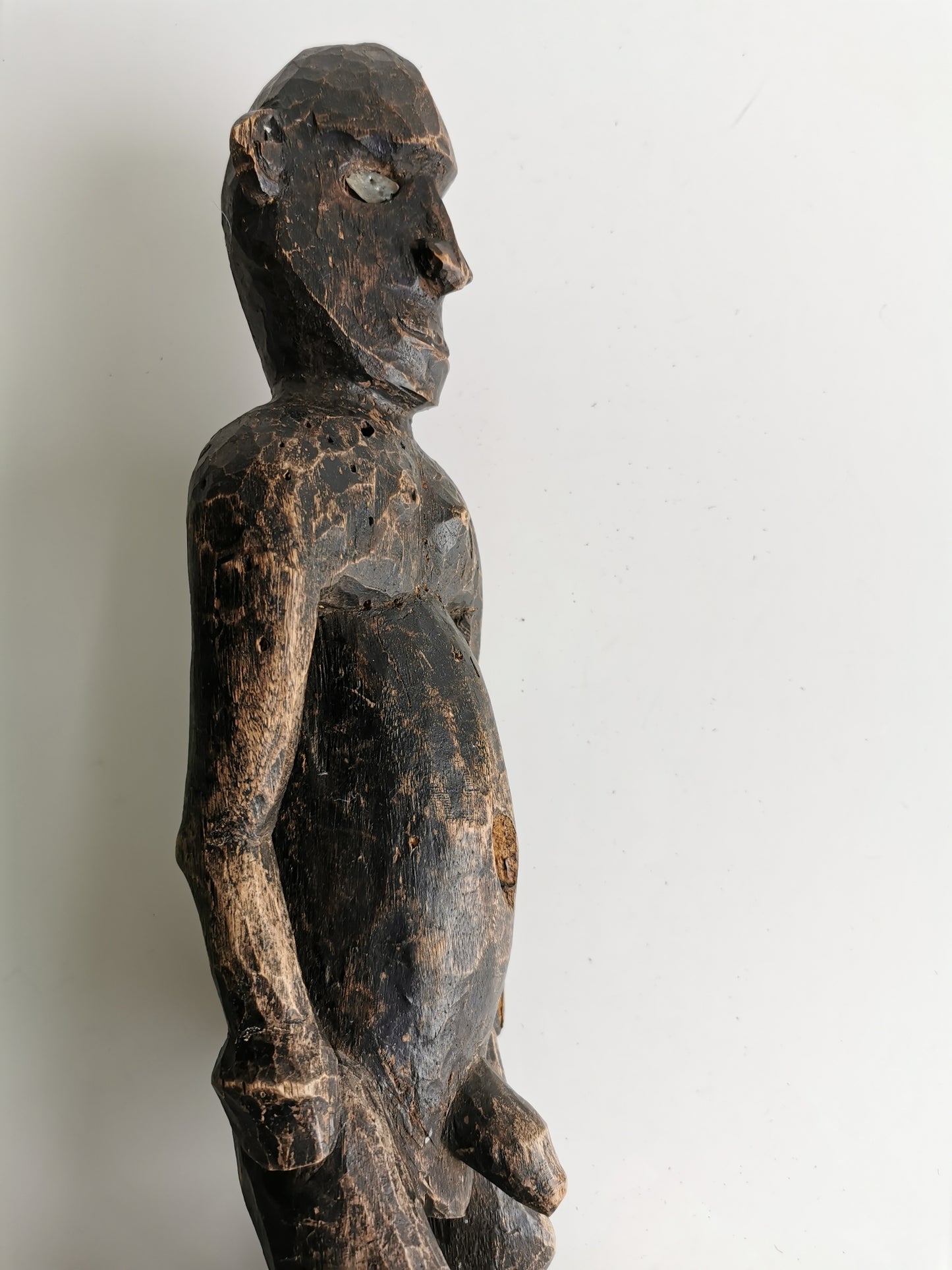 A three-quarter view of the full statue from an angle, showing its position on the stand and the depth of the carving