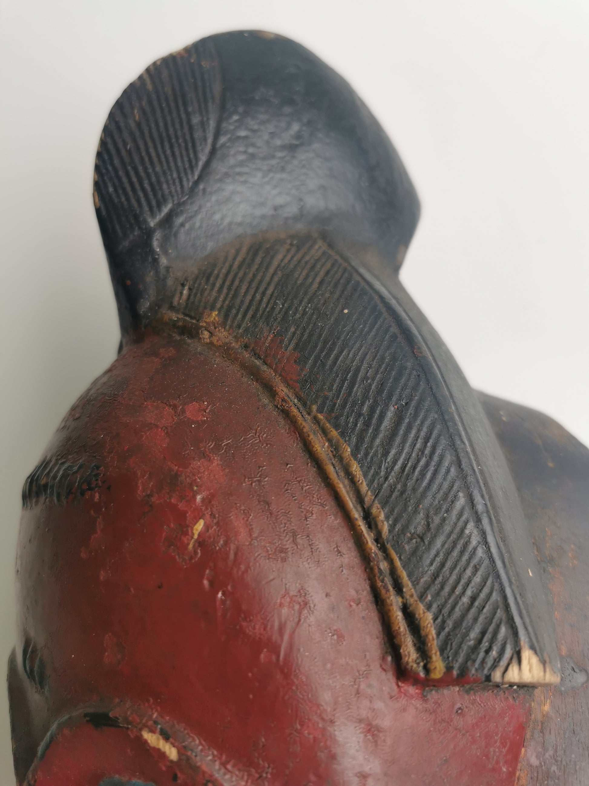 A view of the back of the mask, showing the details of the carved headdress and the smooth, hollowed-out interior.