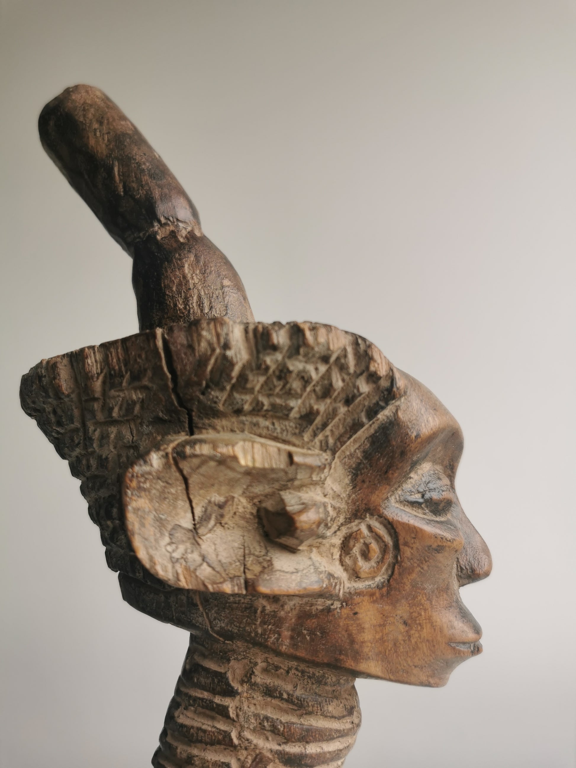A close-up side profile of the statue's head and headdress, highlighting the intricate carving of the face and the tall, tapered top piece