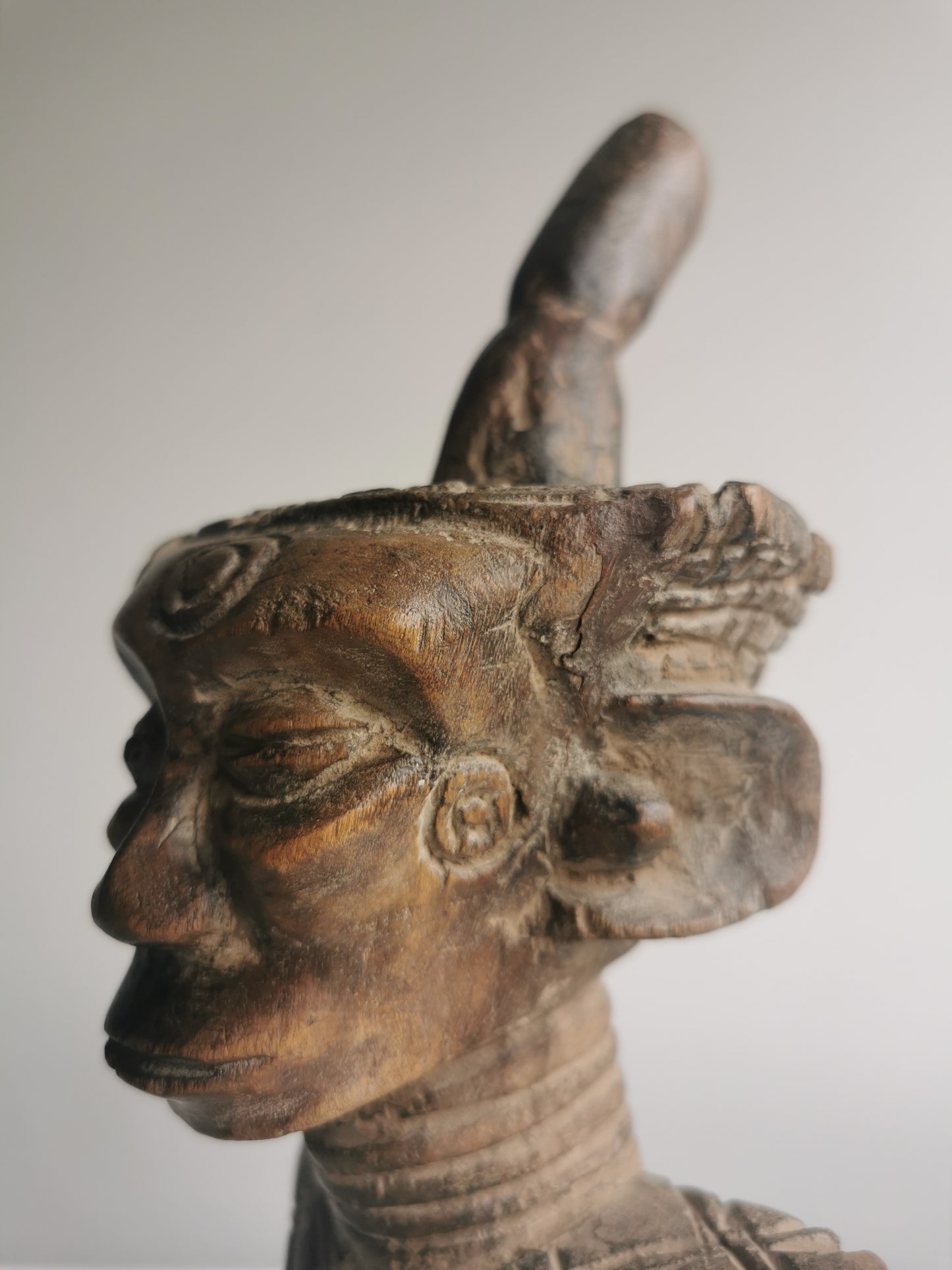 An angled, close-up view of the statue's face, showing the incised patterns and the details of the eyes, nose, and mouth.